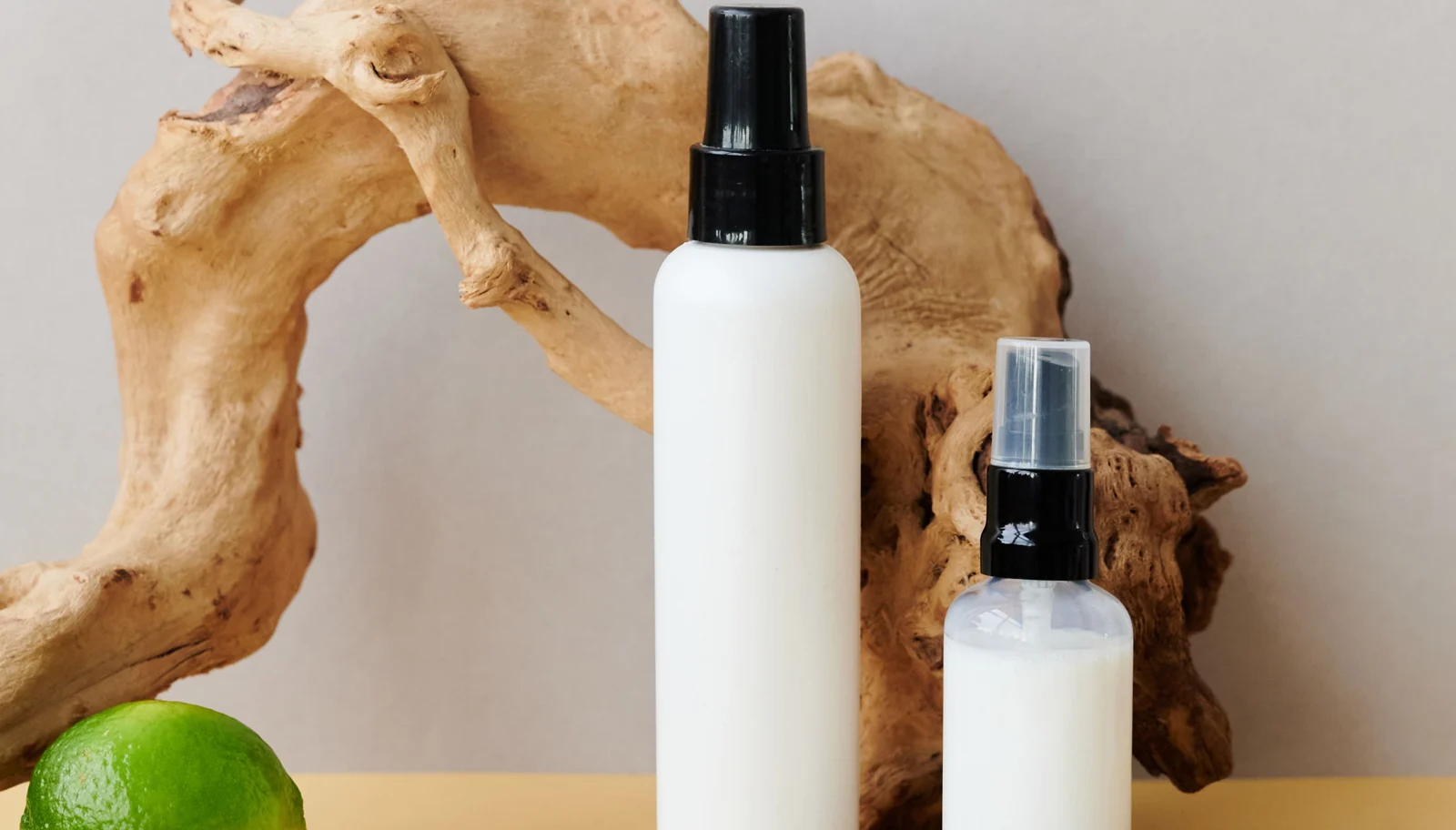 Unbranded white cosmetic spray bottles on a neutral background