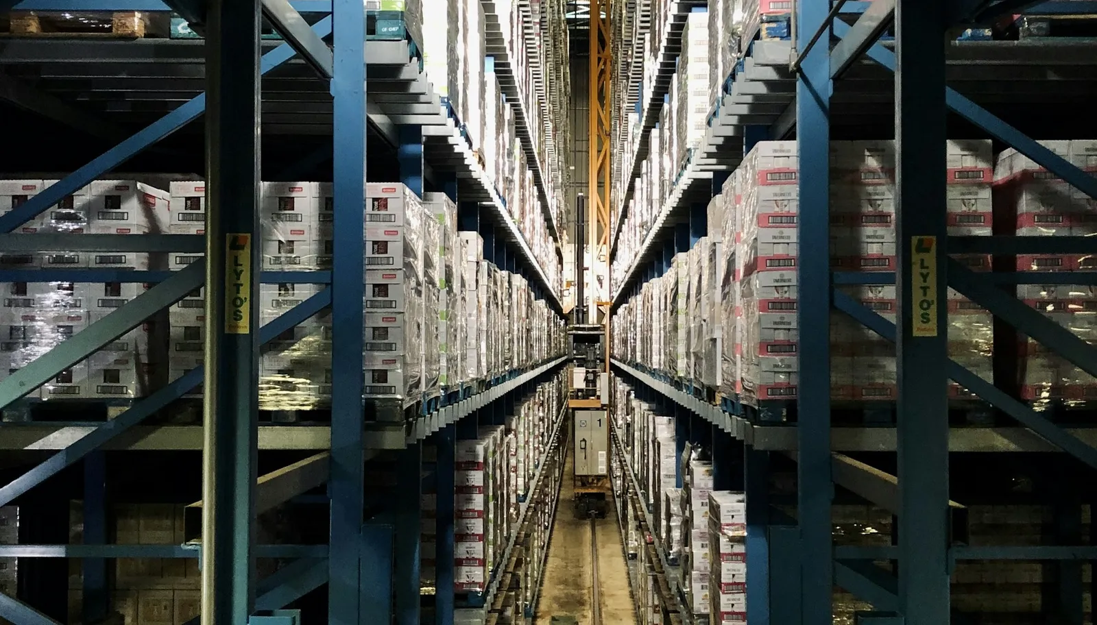 Tall blue warehouse shelving stacked with cardboard boxes along a storage aisle.