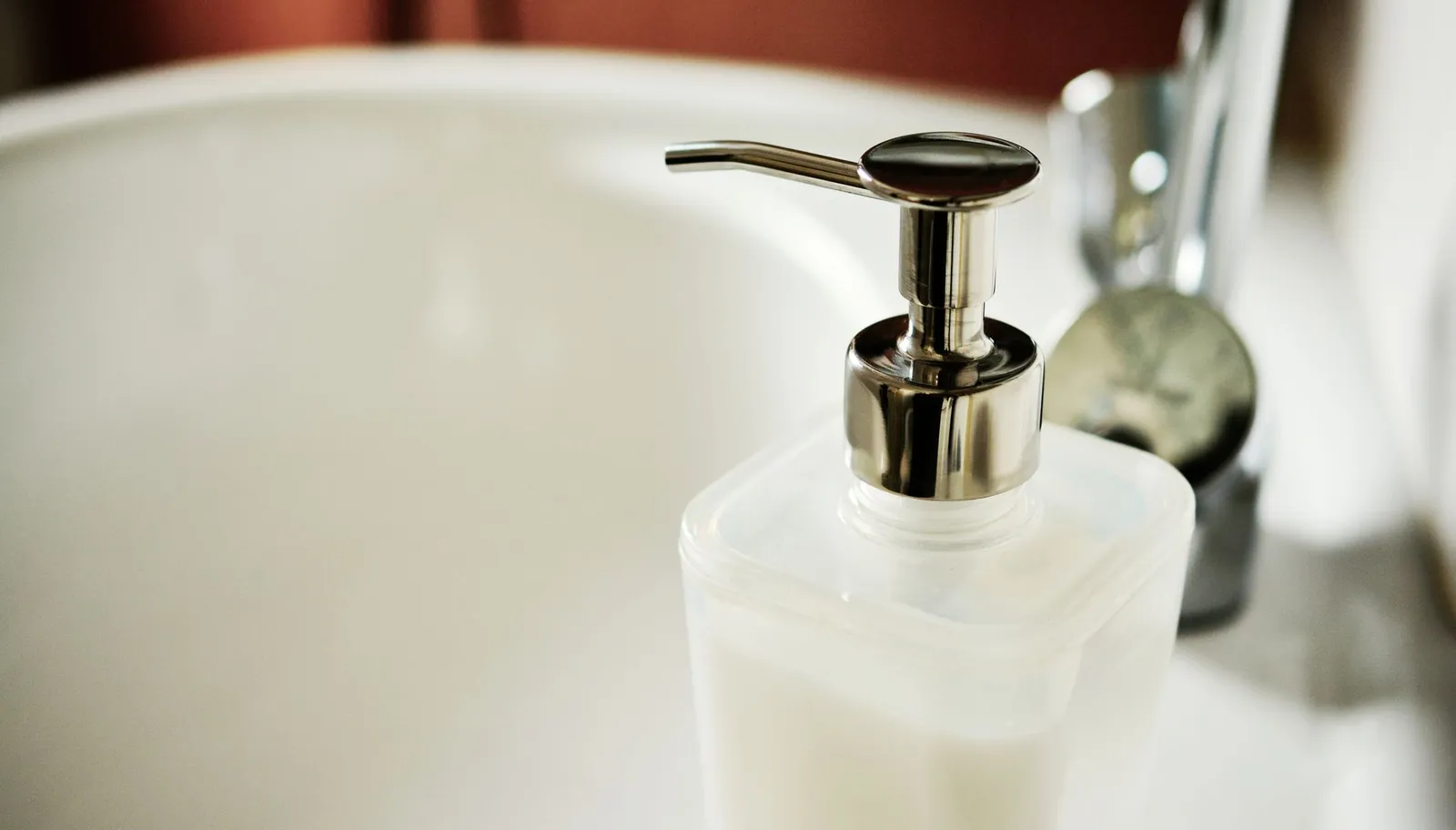 Unbranded pump bottle of hand soap beside a bathroom sink