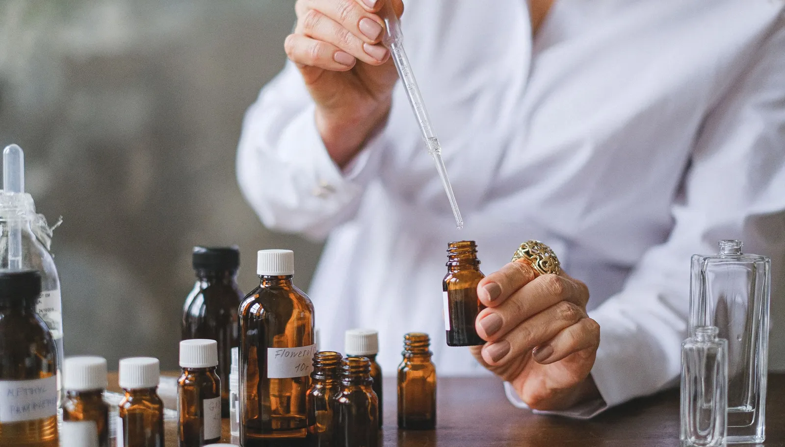 Hands using a glass dropper over amber essential oil bottles