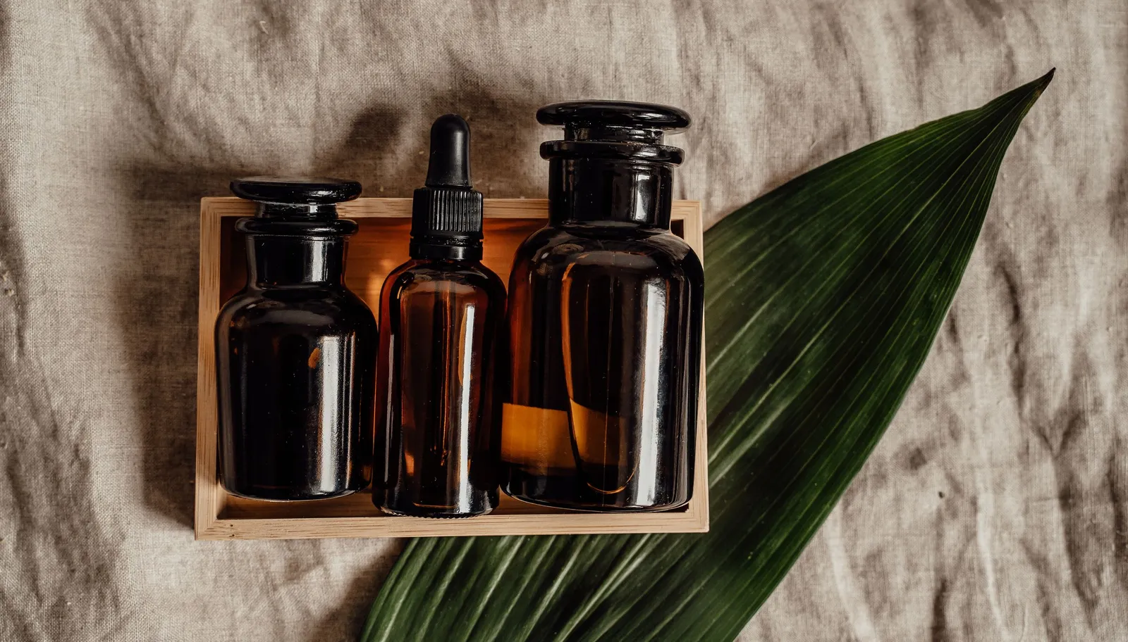 Unlabeled brown glass cosmetic bottles in a wooden box.
