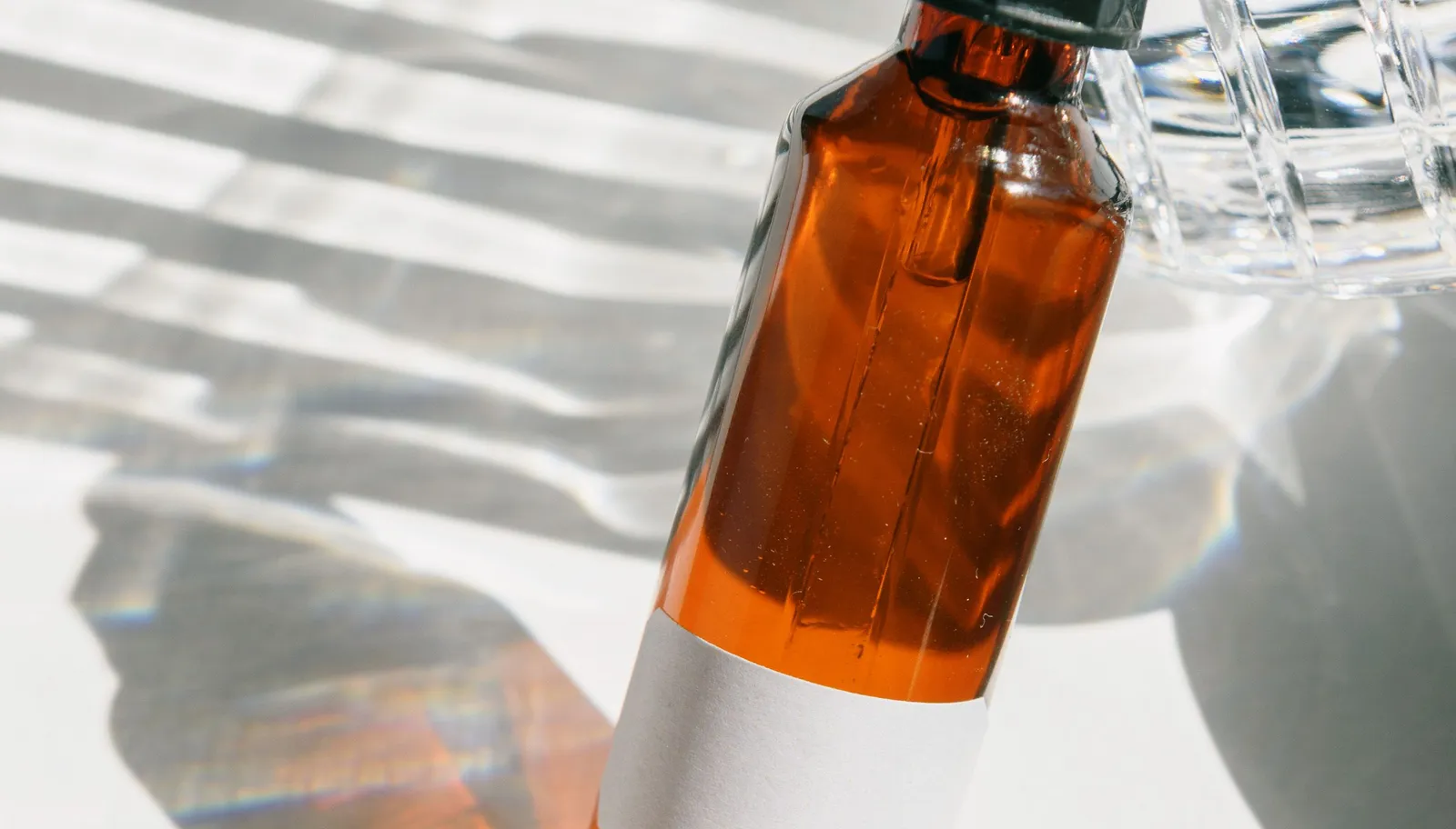 Unlabeled amber glass dropper bottle on a light background, representing testing a formula in its final package